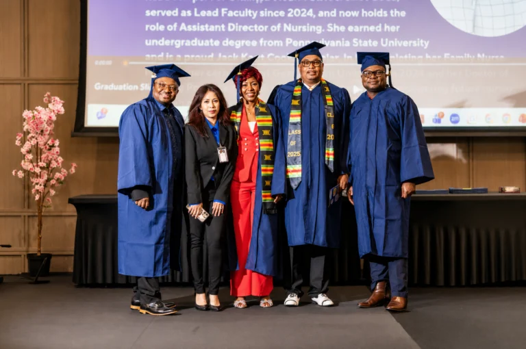 Graduates in caps and gowns posing with two others on a graduation stage.